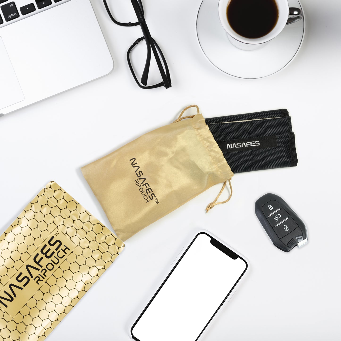 Man sieht ein Esemble auf einem Tisch. Es sieht wie ein Arbeitsplatz aus und es liegt ein Handy und ein Keyless Go Autoschlüssel auf dem Tisch. In der Mitte sieht man die Nasafes Abschirmtasche und die schicke goldene Verpackung dieser Tasche. Die Tasche kann als Rfid Autoschlüssel Schutz und als Strahlenblocker für Handy agieren. Als Schutzhülle für Autoschlüssel oder als Anti Tracking Handyhülle. Je nachdem für was man die Tasche benutzt, sie schirmt jegliche Signale effektiv ab.