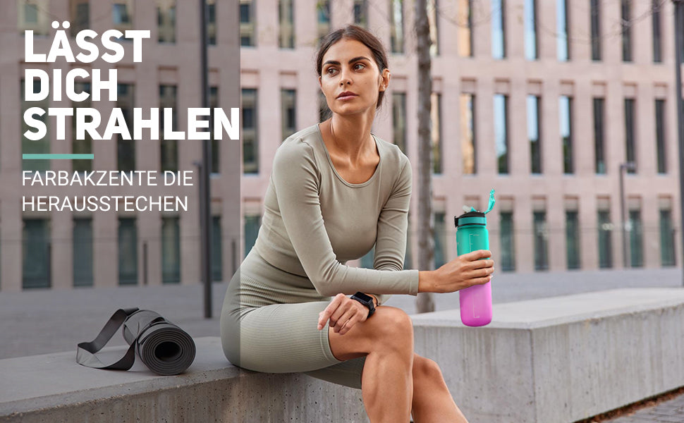 Die Trainingsflasche ist super für Sport und Joga geeignet. Darum sieht man eine junge Frau in einer urbanen Umgebung sitzen, die eine Motivationsflasche in der Hand hält. Es ist eine Smart Trinkflasche, weil die Trinkflasche Tagesbedarf den genauen Wasserbedarf anzeigt.